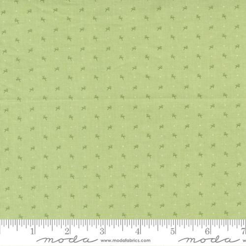 Small green floral clusters and faint white dots on a light green background. Fabric